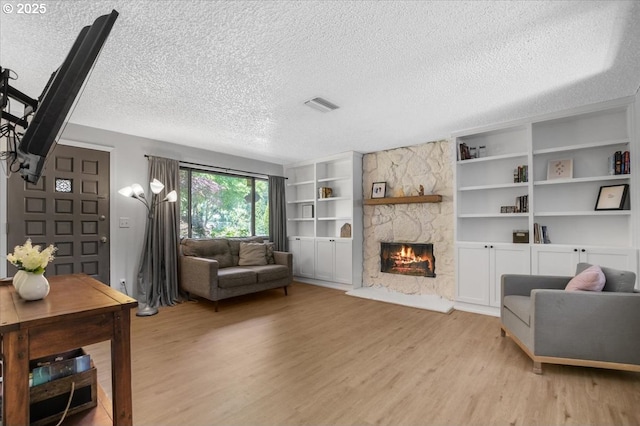 9532 SW Whitford Ln, Beaverton, OR 97008 - living area with light wood finished floors, a stone fireplace, a textured ceiling, and built in features