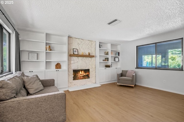 9532 SW Whitford Ln, Beaverton, OR 97008 - living room with a textured ceiling, light wood-type flooring, a stone fireplace, built in features, and baseboards