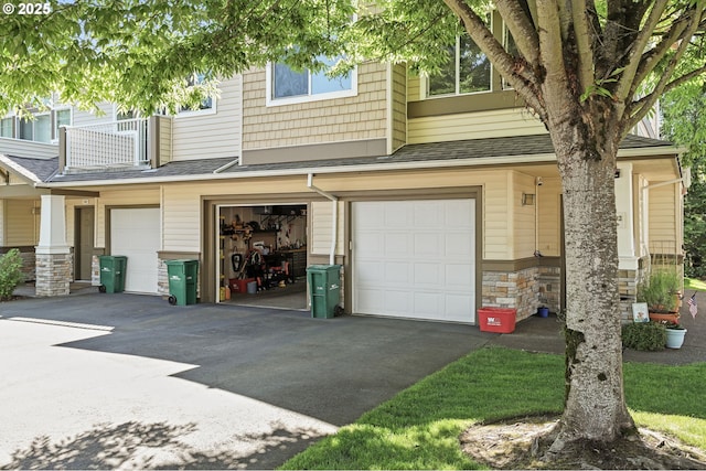 14600 SW Magpie Ln Unit 102, Beaverton, OR 97007 - view of front of house with an attached garage, asphalt driveway, stone siding, and a shingled roof