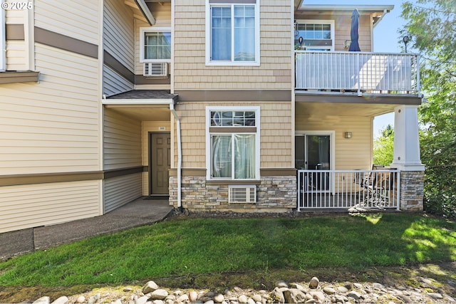 14600 SW Magpie Ln Unit 102, Beaverton, OR 97007 - view of exterior entry with a balcony, stone siding, and a yard