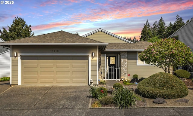 ranch-style house featuring roof with shingles, concrete driveway, and a garage
