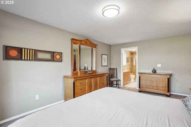 carpeted bedroom featuring a textured ceiling, ensuite bathroom, and baseboards