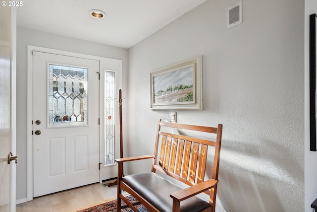 foyer with light wood-type flooring, baseboards, and visible vents