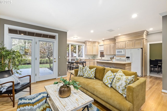 living room with light wood-style floors, recessed lighting, visible vents, and crown molding