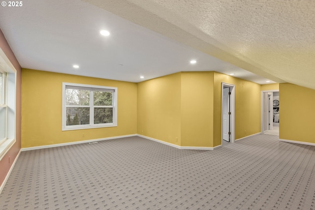 additional living space featuring recessed lighting, light colored carpet, a textured ceiling, and baseboards