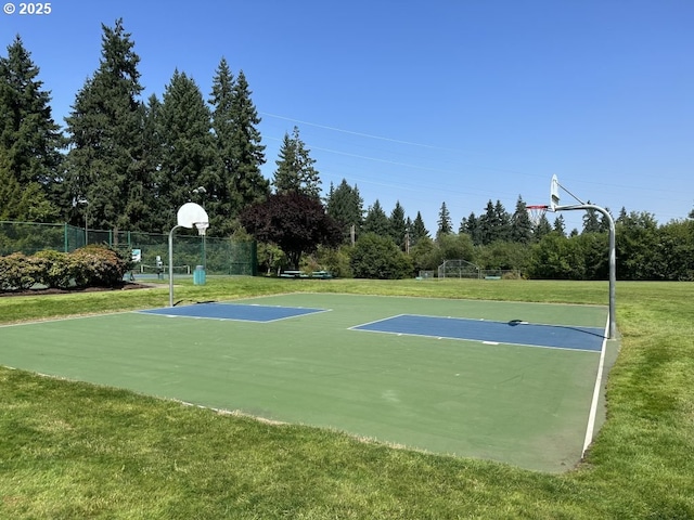 view of basketball court with community basketball court, fence, and a yard