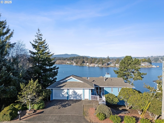 ranch-style house with a garage, concrete driveway, and a water view