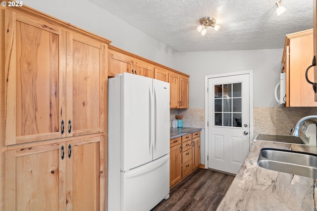 kitchen with dark hardwood / wood-style flooring, backsplash, white appliances, a textured ceiling, and sink