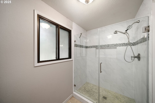 bathroom featuring a shower stall, baseboards, and a textured ceiling