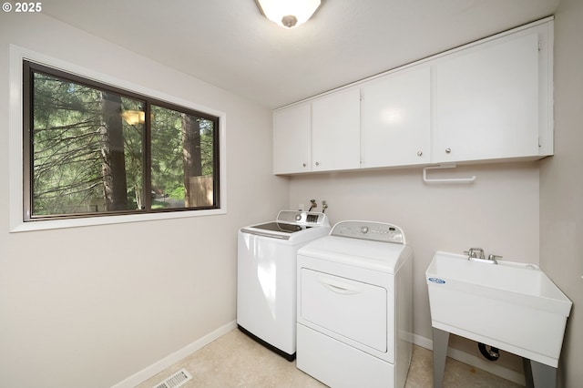 washroom with washing machine and clothes dryer, cabinet space, and baseboards