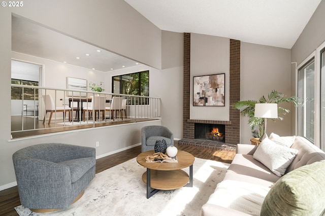 living room featuring wood finished floors, a brick fireplace, baseboards, and high vaulted ceiling
