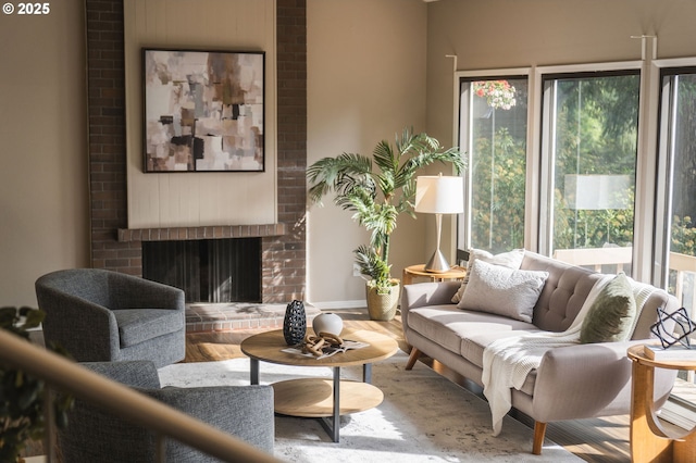 living room with wood finished floors, baseboards, and a brick fireplace