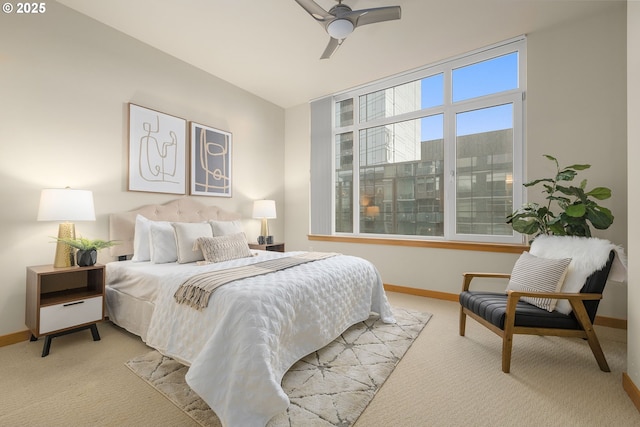 bedroom with a ceiling fan, light carpet, and baseboards