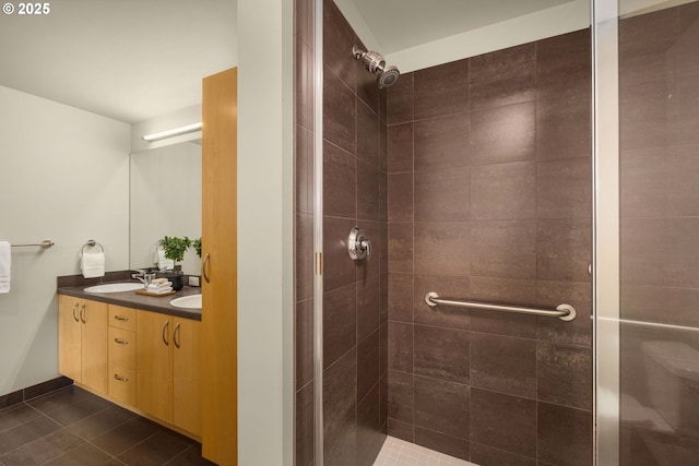 full bathroom with tile patterned flooring, a sink, baseboards, tiled shower, and double vanity