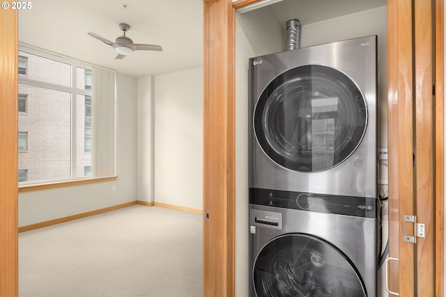 washroom featuring stacked washer and dryer, laundry area, baseboards, a ceiling fan, and carpet floors