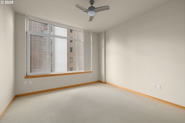 carpeted spare room with a ceiling fan, plenty of natural light, and baseboards