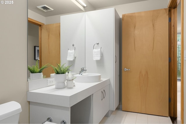 half bathroom featuring toilet, tile patterned flooring, visible vents, and vanity