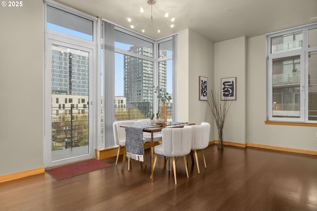 dining space featuring baseboards, dark wood finished floors, a wall of windows, a city view, and a notable chandelier