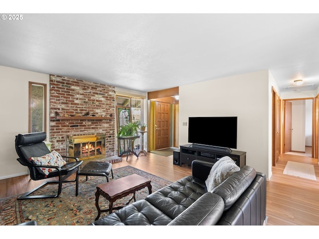 living area with a textured ceiling, light wood-style flooring, and a fireplace