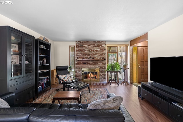 living room featuring a brick fireplace and wood finished floors