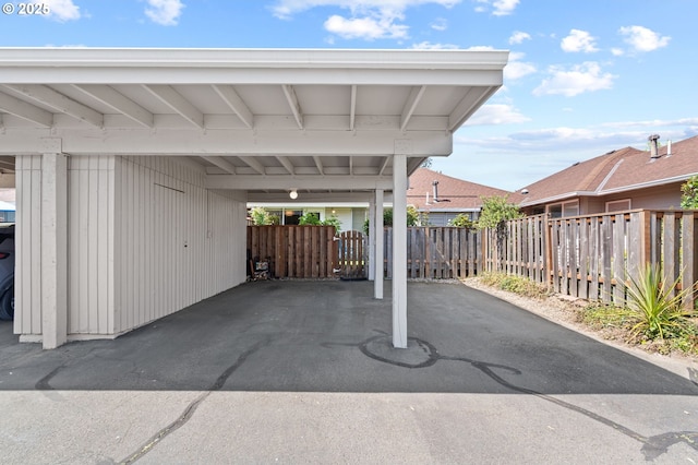 view of vehicle parking featuring fence, a carport, and aphalt driveway