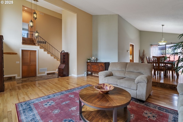 living area with baseboards, stairs, high vaulted ceiling, and wood finished floors