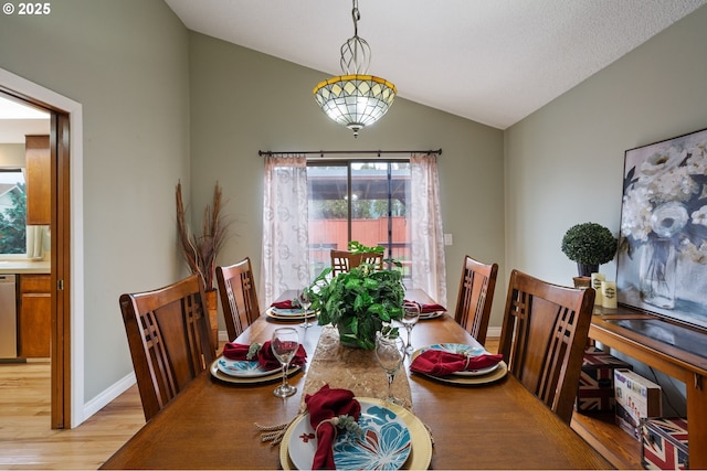 dining room with vaulted ceiling, light wood-style flooring, and baseboards