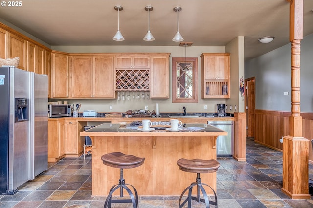 3360 NW Oceanview Dr, Newport, OR 97365 - kitchen with appliances with stainless steel finishes, stone tile flooring, a center island, a breakfast bar area, and a wainscoted wall
