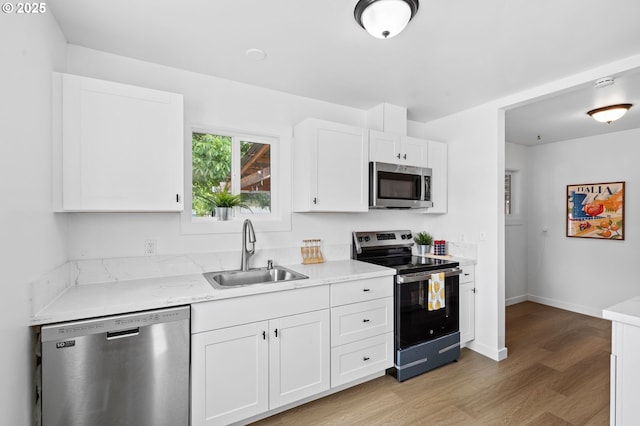 3235 SE 69th Ave, Portland, OR 97206 - kitchen with appliances with stainless steel finishes, light wood finished floors, and white cabinets