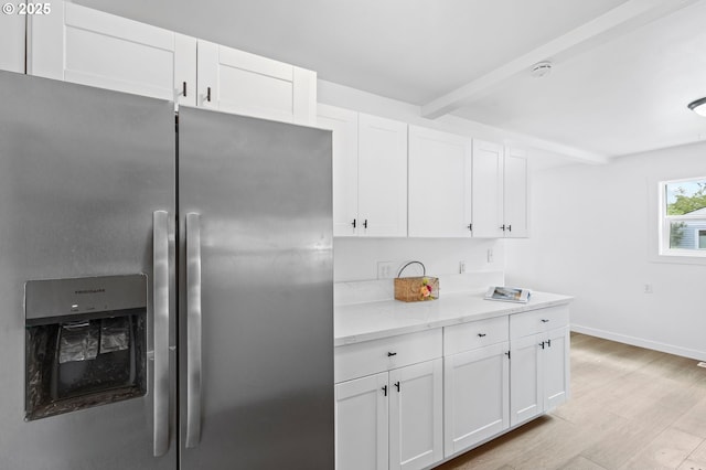 3235 SE 69th Ave, Portland, OR 97206 - kitchen with stainless steel fridge, light wood-type flooring, white cabinetry, beam ceiling, and light stone countertops