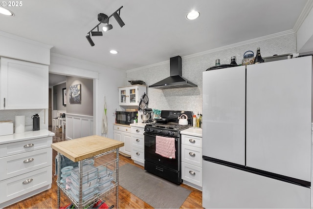 190 Walnut St, Myrtle Creek, OR 97457 - kitchen with freestanding refrigerator, wall chimney exhaust hood, black gas range oven, crown molding, and white cabinetry