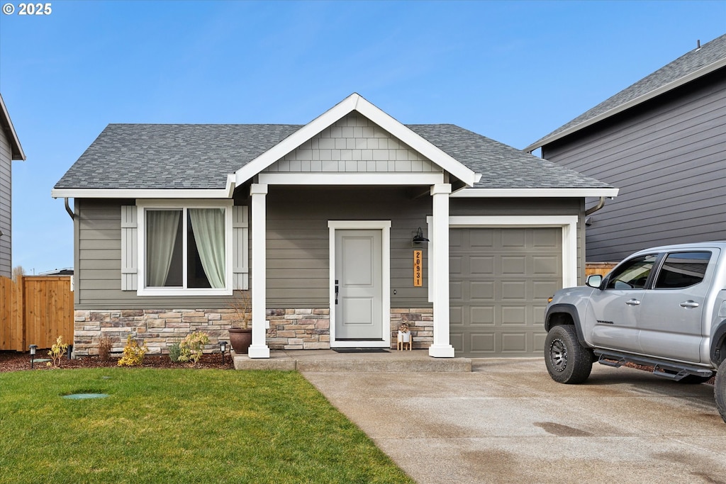 view of front facade with a shingled roof, concrete driveway, an attached garage, fence, and a front lawn