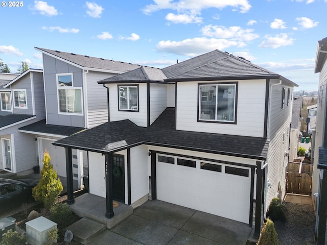 view of front facade featuring a shingled roof, driveway, and a garage