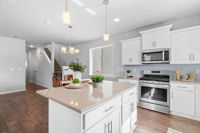 kitchen with appliances with stainless steel finishes, backsplash, wood finished floors, and visible vents