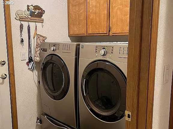 laundry room with washer and clothes dryer and cabinets