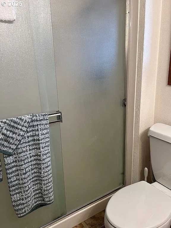 bathroom featuring toilet and a shower with shower door