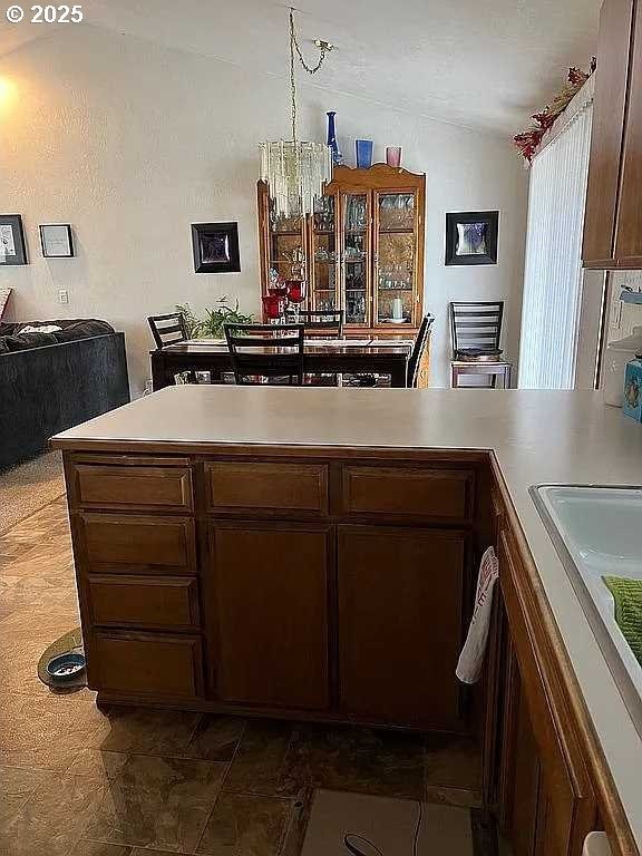 kitchen featuring sink, lofted ceiling, a chandelier, and decorative light fixtures