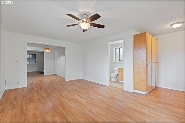 unfurnished living room with baseboards, a textured ceiling, ceiling fan, and light wood finished floors