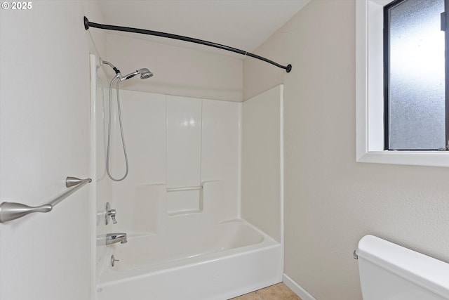 full bath featuring tile patterned floors, toilet, bathing tub / shower combination, and baseboards