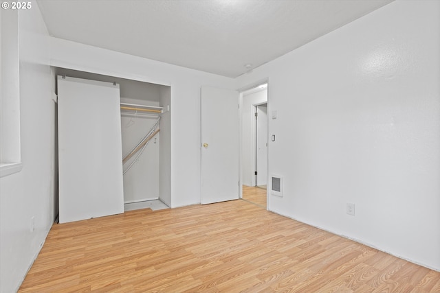 unfurnished bedroom with a closet, visible vents, and wood finished floors