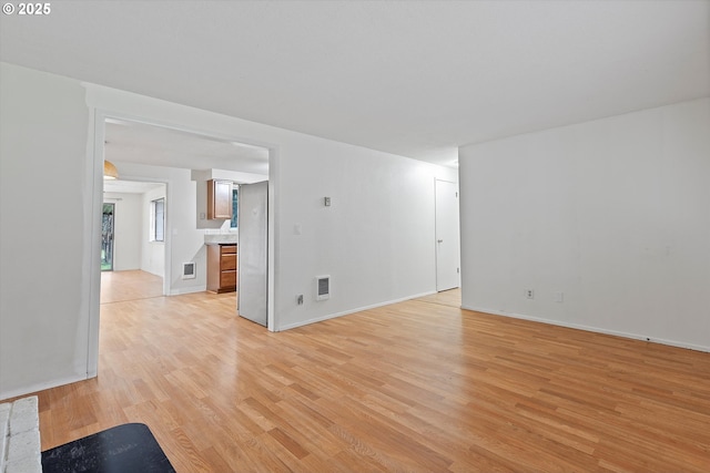 unfurnished living room featuring visible vents, baseboards, and light wood finished floors