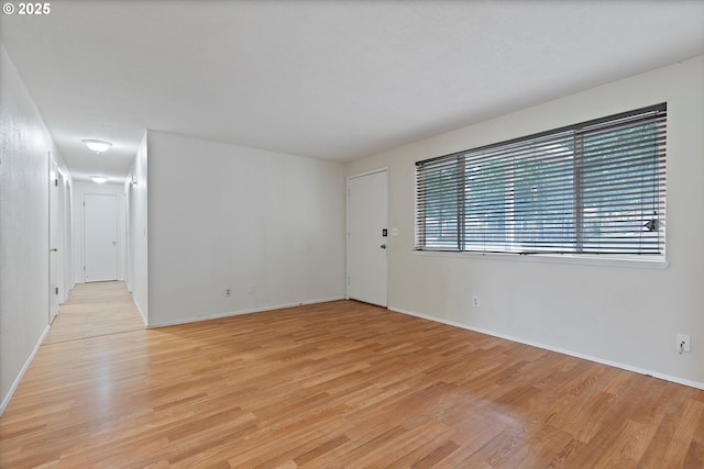 spare room featuring light wood-style flooring and baseboards