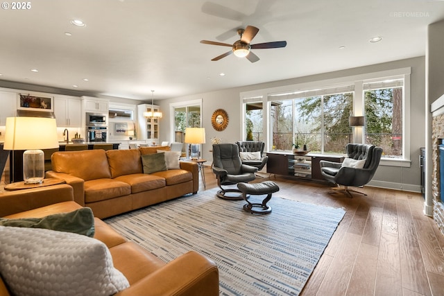 living area featuring ceiling fan with notable chandelier, hardwood / wood-style flooring, recessed lighting, and a fireplace