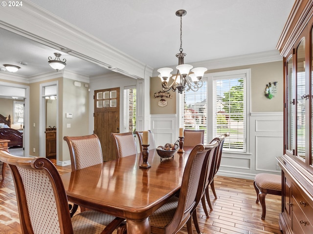 dining space with a chandelier, a decorative wall, light wood-type flooring, and ornamental molding