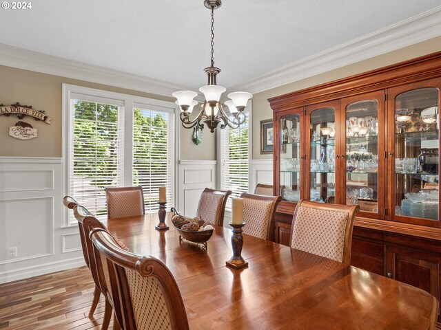 dining room with ornamental molding, hardwood / wood-style floors, and a notable chandelier