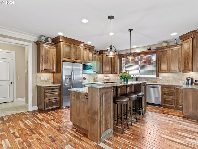 kitchen with stainless steel appliances, light stone countertops, a kitchen island, and backsplash