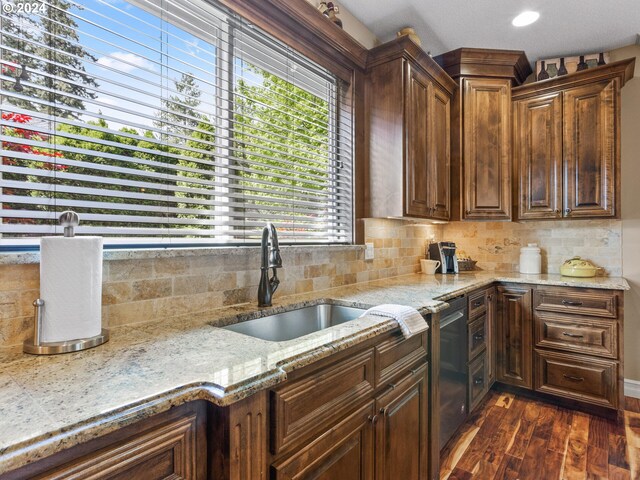 kitchen featuring sink, light stone counters, backsplash, and dark hardwood / wood-style flooring