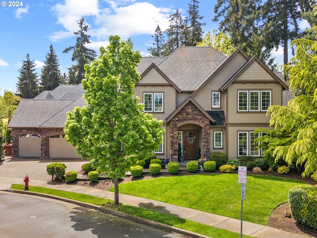 craftsman house with driveway, stone siding, a front yard, a shingled roof, and a garage