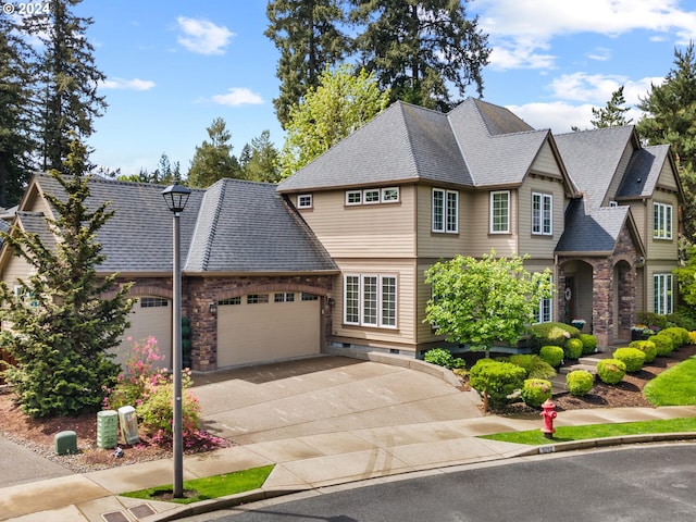 view of front facade with an attached garage, driveway, and a shingled roof