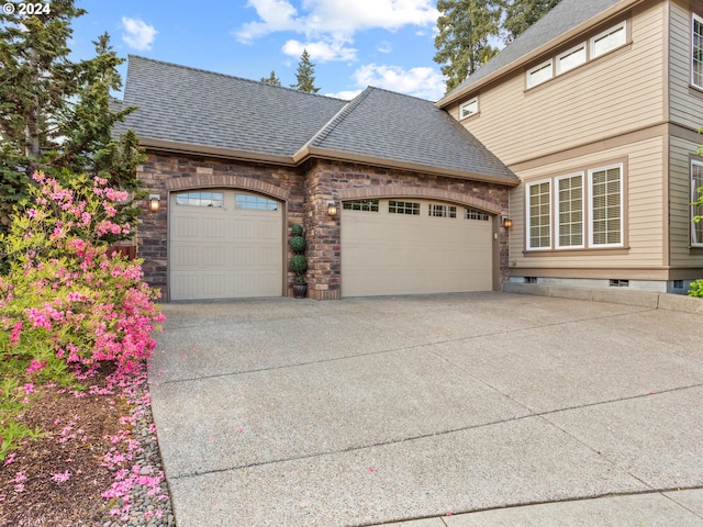 view of home's exterior with concrete driveway, an attached garage, and a shingled roof